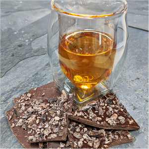 Whiskey Nib Bark with a glass of whiskey on slate